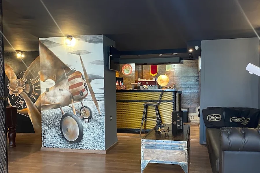 Salon Barber Shop Factory avec sa fresque d'avion, son bar et son canapé Chesterfield
