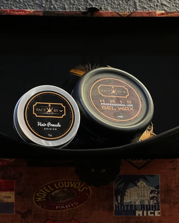 Pommade et gel wax de la gamme Factory posés sur une malle vintage