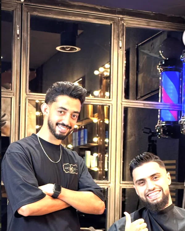 Client satisfait avec la cape Factory devant l'enseigne barbier
