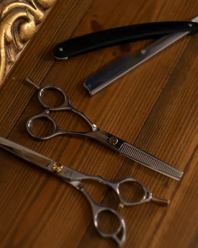 Ciseaux et rasoir de barbier posés sur un plan de travail en bois